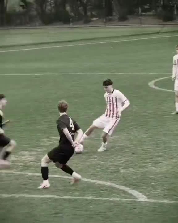 Attacker in red and white stripes strikes the ball past a defender