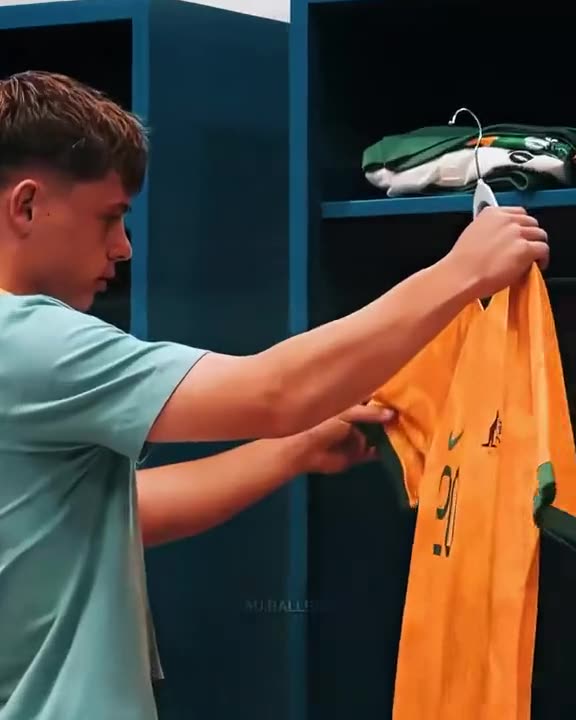 Young player hanging a green and gold Australia shirt in the change room