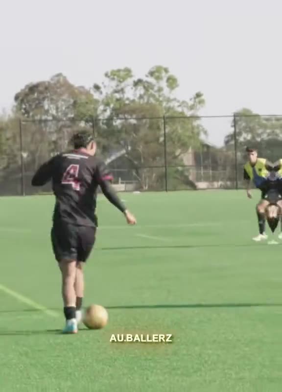 Player in black and pink drives forward with the ball during a junior match